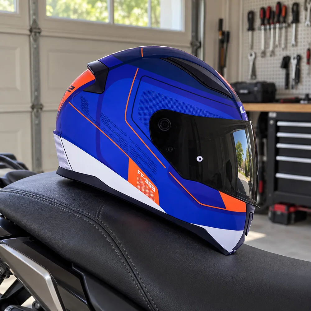 Capacete fechado azul com detalhes laranja e branco, sobre o banco de uma moto, com painel de ferramentas ao fundo