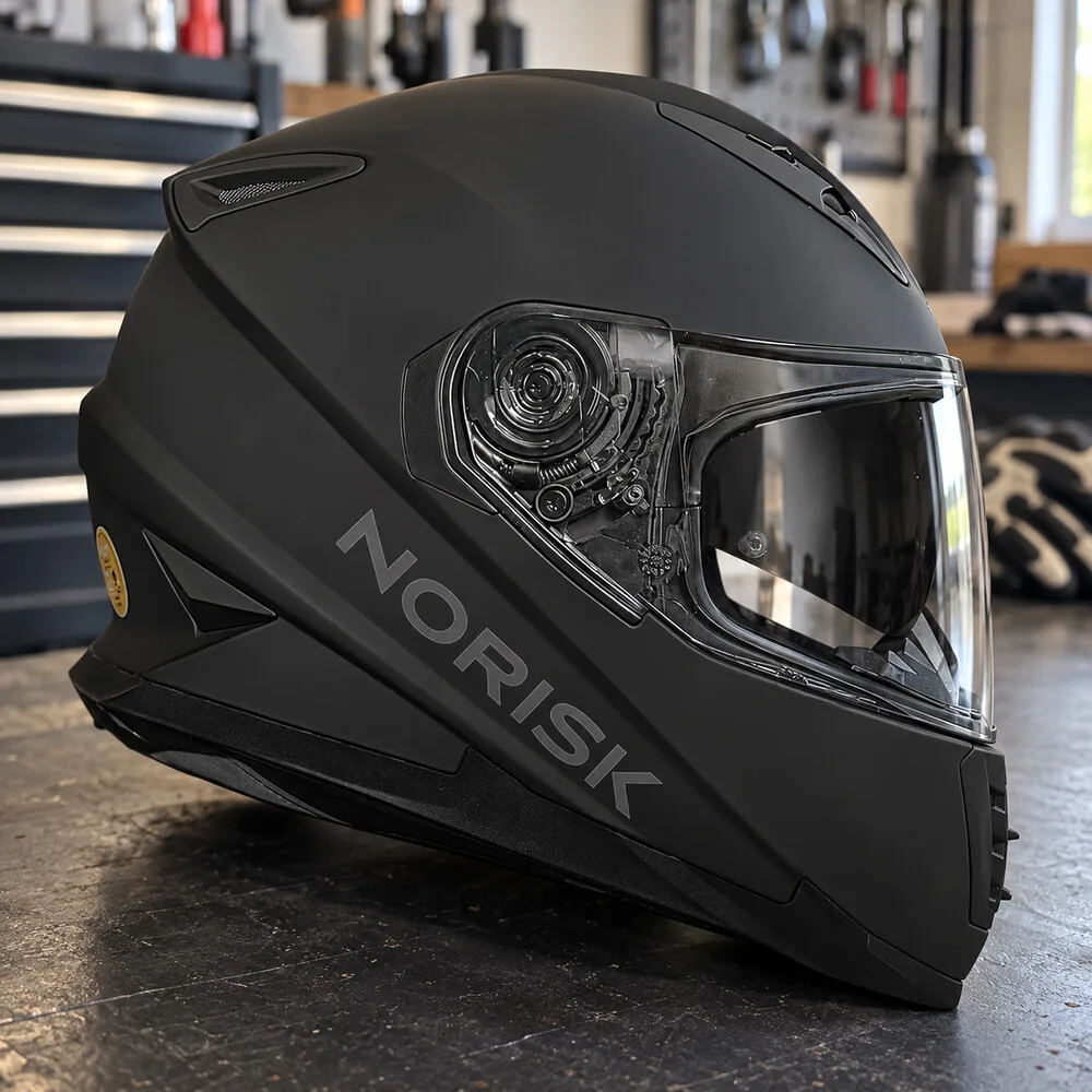 Capacete fechado preto fosco com a marca na lateral, sobre uma bancada de oficina